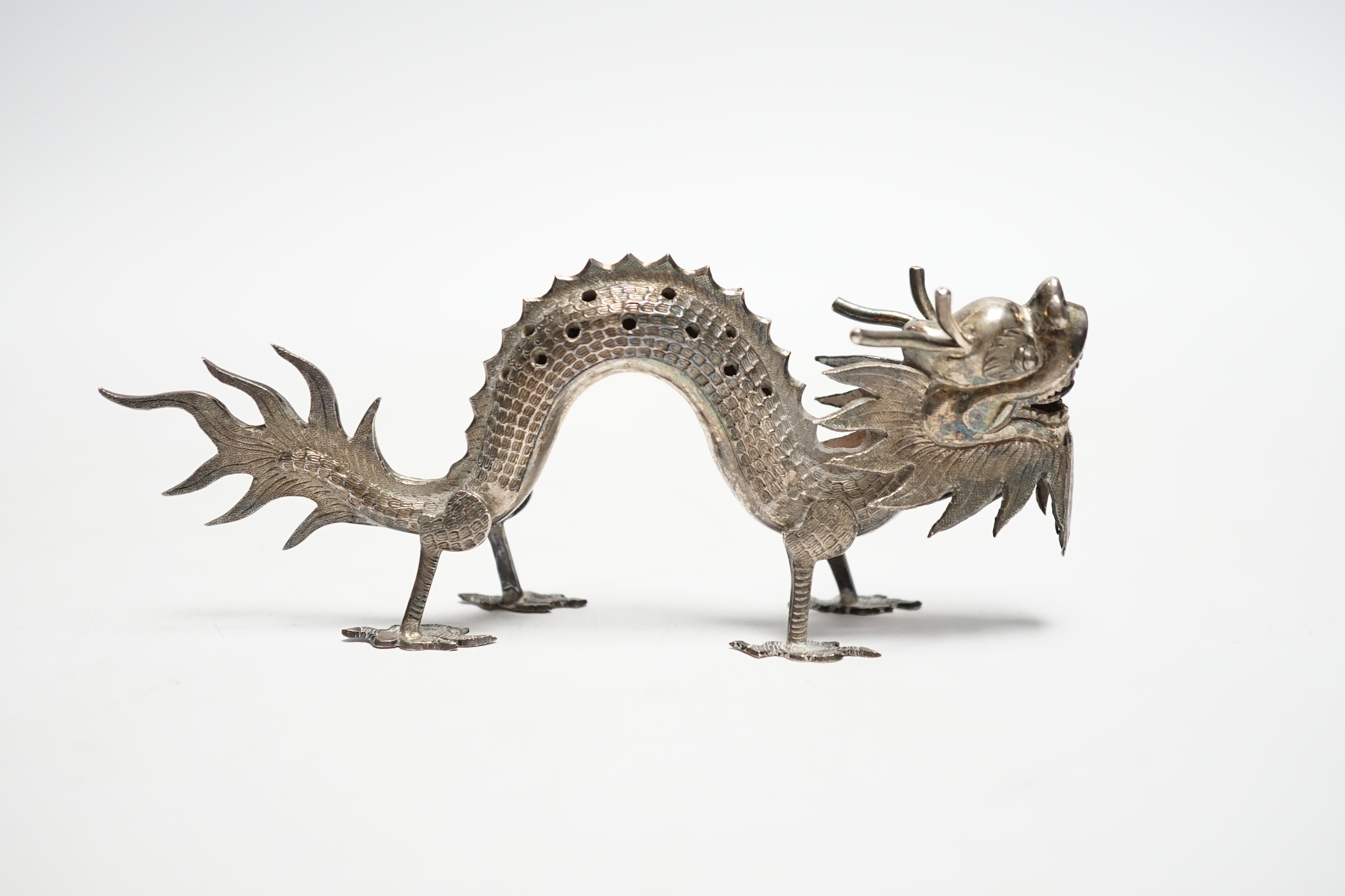 A Chinese white metal toothpick holder, modelled as a free standing model of a dragon, 12.4cm.